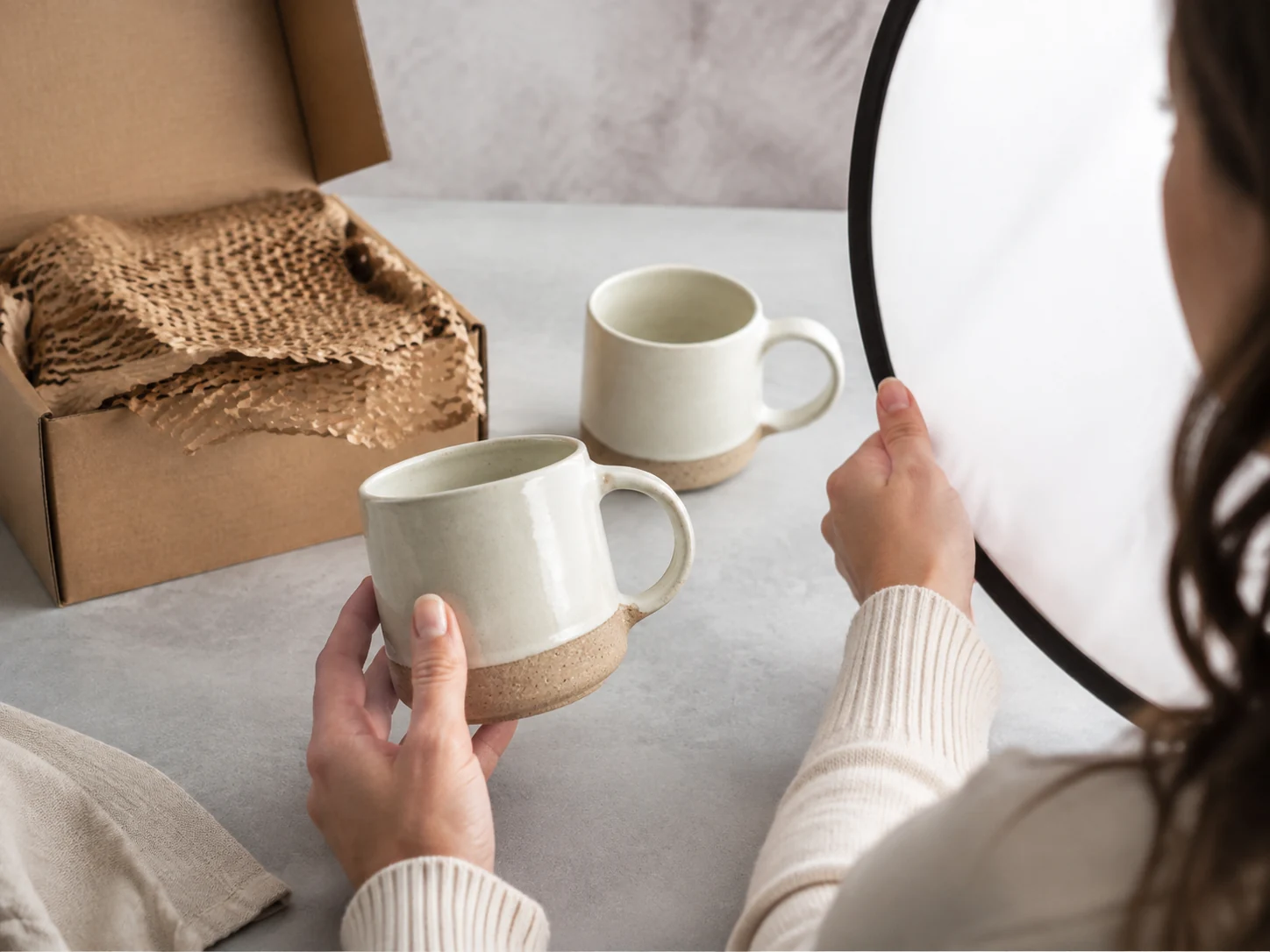 A maker photographs a ceramic mug in a hand to communicate scale and real use.